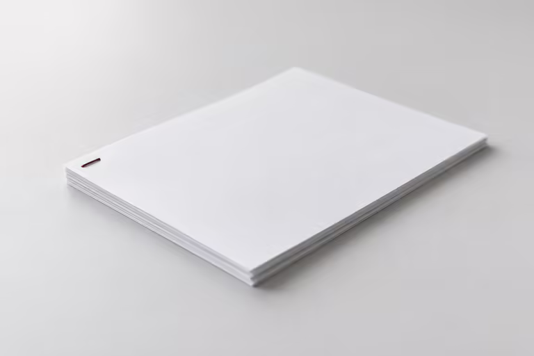 A small sheaf of white paper stapled at one corner with a single dark red staple, on a grey surface