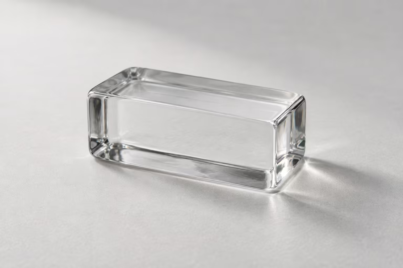 A clear glass block on a grey surface, the surface visible through it